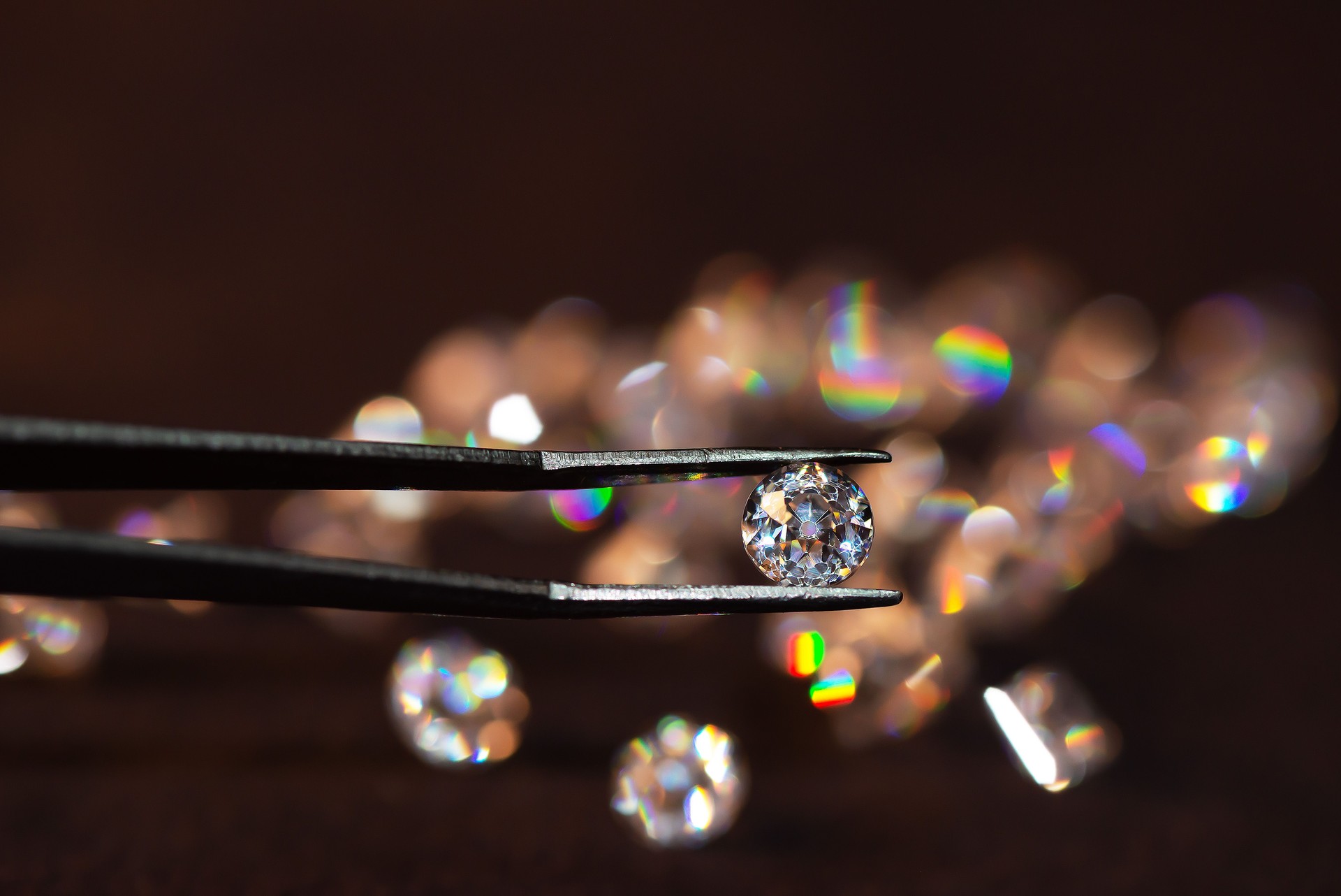 Diamant in Pinzette auf dunklem Hintergrund mit Diamanten Gruppe weiche Fokussierung