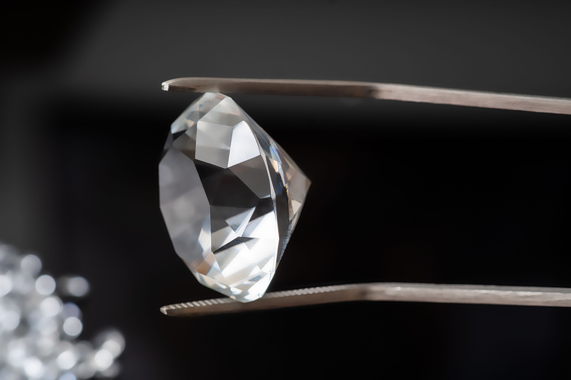 Luxus-Diamant in Pinzette auf schwarzem Hintergrund.